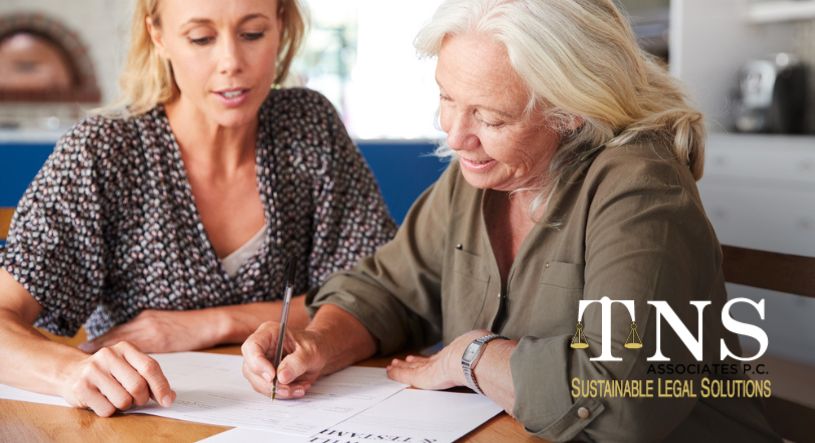 female friend helping senior woman to complete last will and testament at home